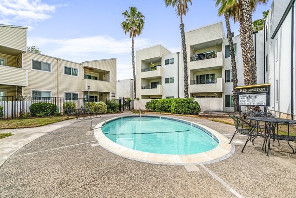 Luxurious poolside retreat at Kensington Apartments featuring sun loungers and lush landscaping