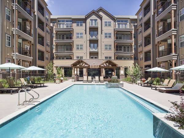 Infinity-edge pool surrounded by lounge chairs at Village at Aspen Place Apartments, a luxury living community in Flagstaff