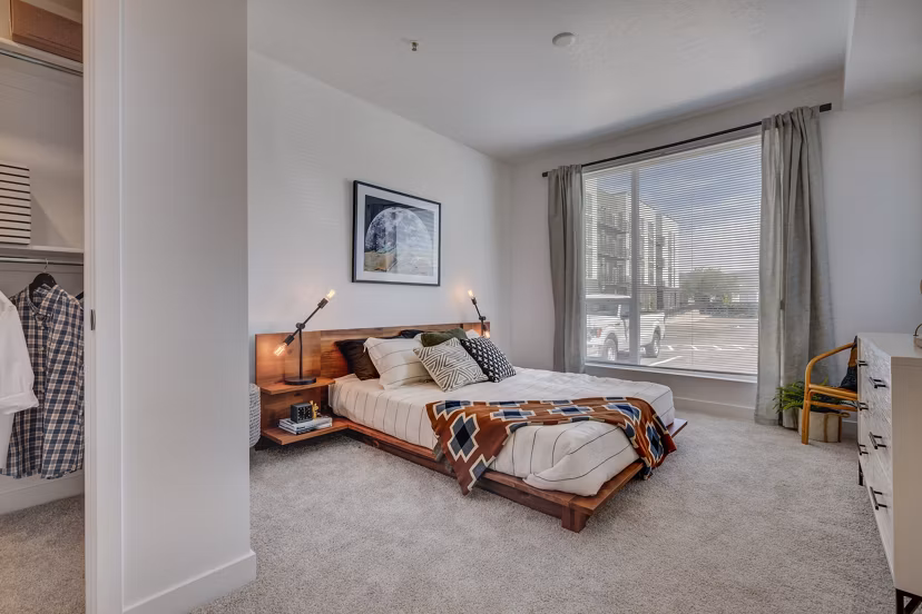 Cozy bedroom with plush bedding in Meridian Apartments, featuring subtle lighting and ample closet space for luxury living