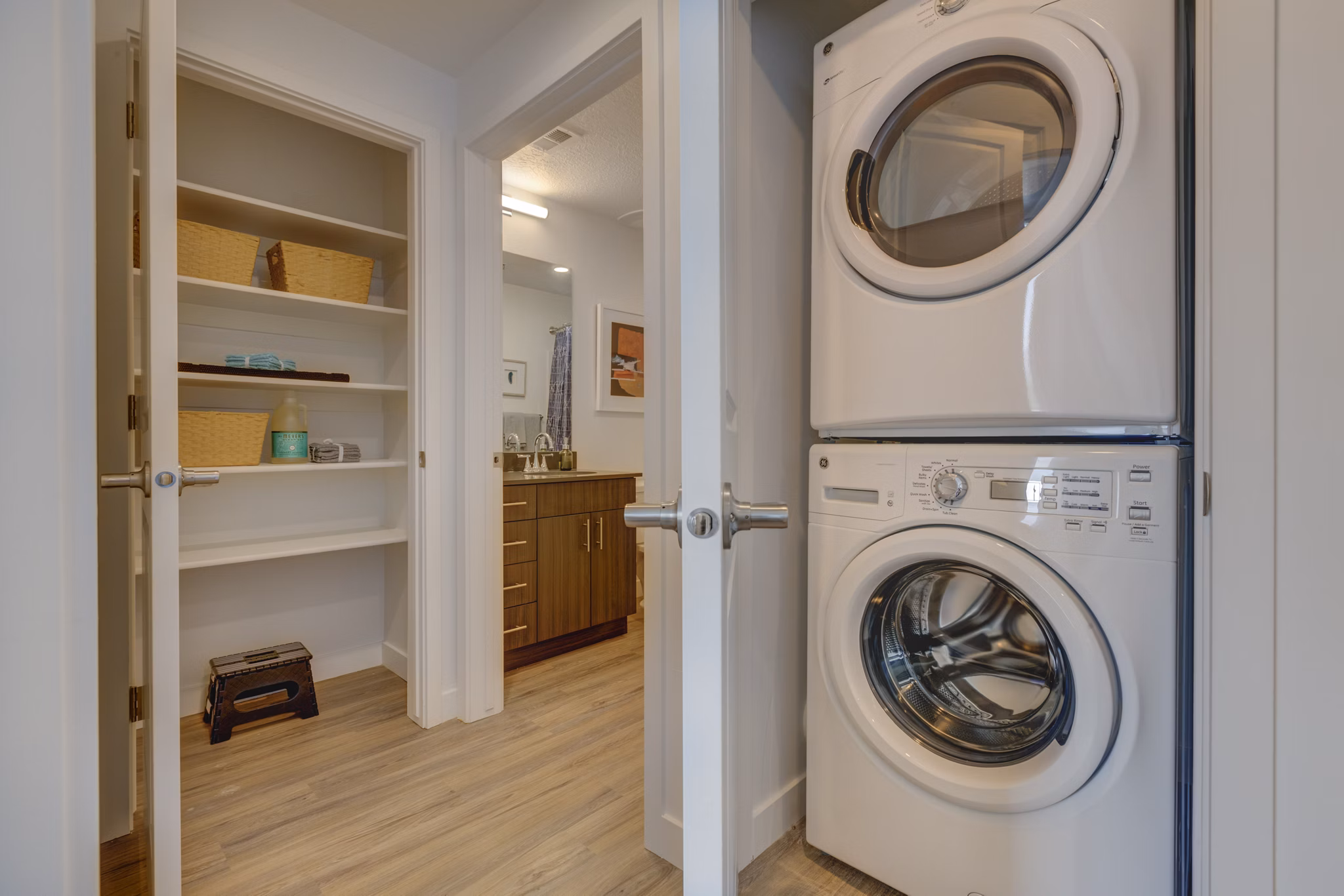 Laundry room with modern appliances and ample shelving at Meridian Apartments