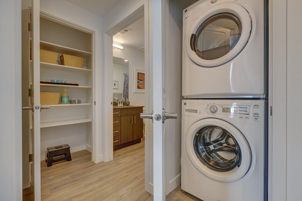 Laundry room with modern appliances and ample shelving at Meridian Apartments