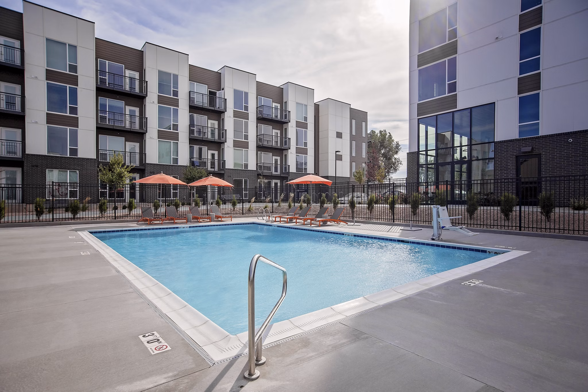 Modern outdoor pool at Meridian Apartments offering relaxing poolside seating and lush landscaping