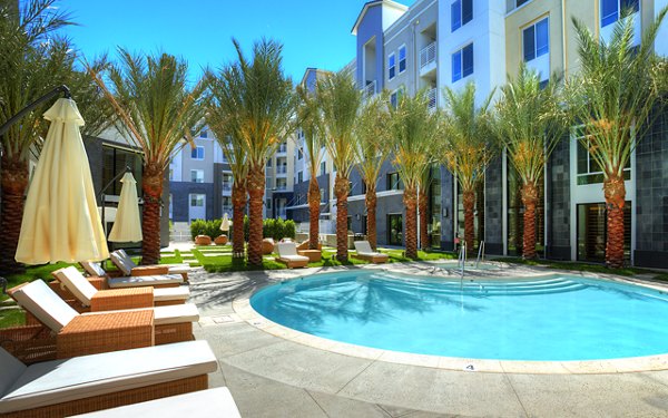 Luxurious pool at Eton at Warner Center Apartments with palm trees and lounge chairs, offering resort-style relaxation in the heart of the city