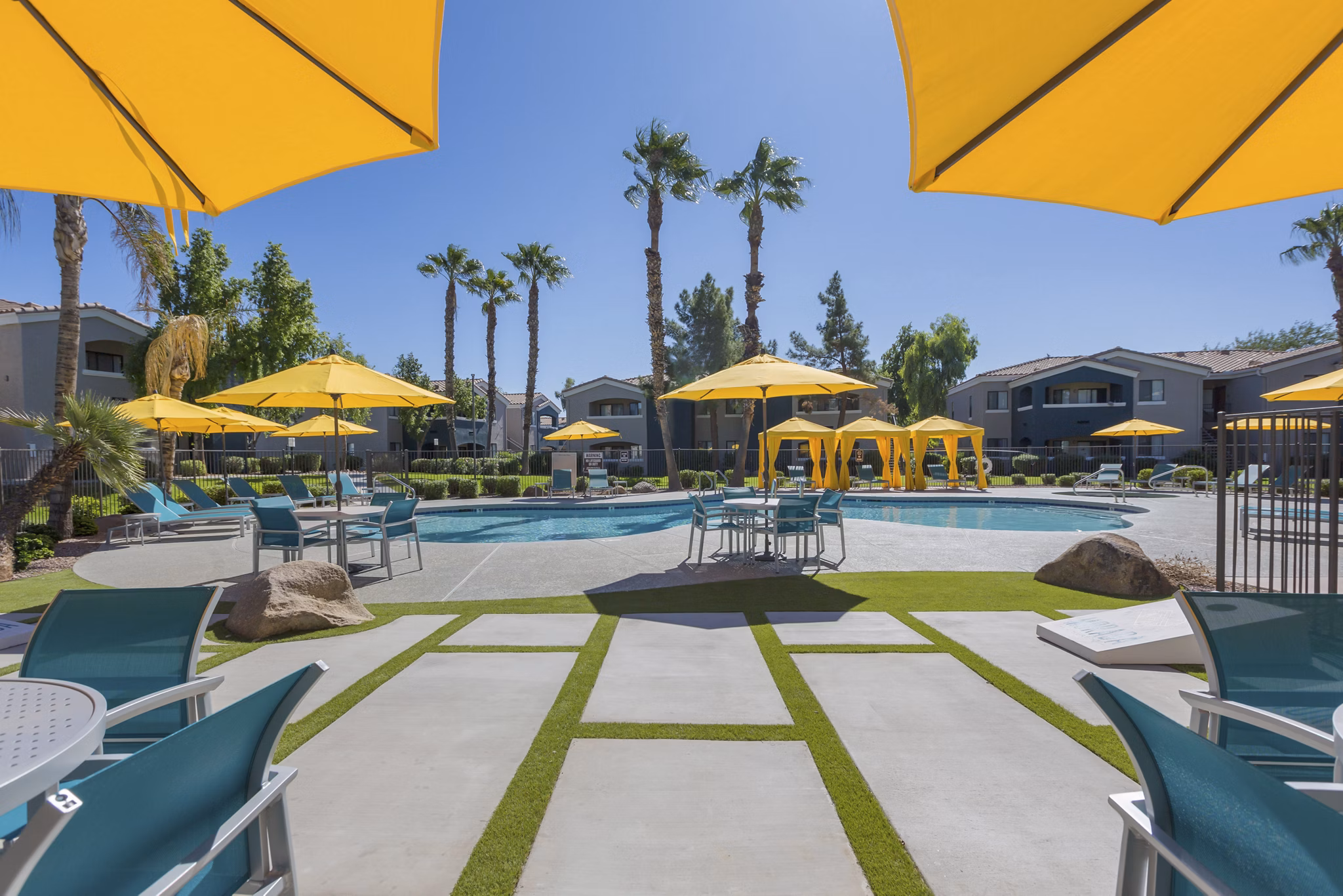 Resort-style swimming pool at Morada West Apartments featuring lounge chairs and greenery