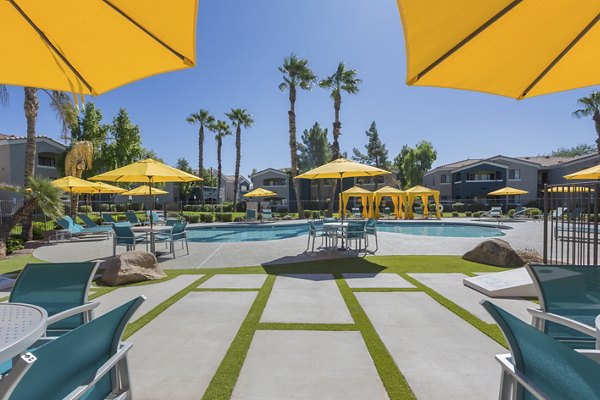 Resort-style swimming pool at Morada West Apartments featuring lounge chairs and greenery