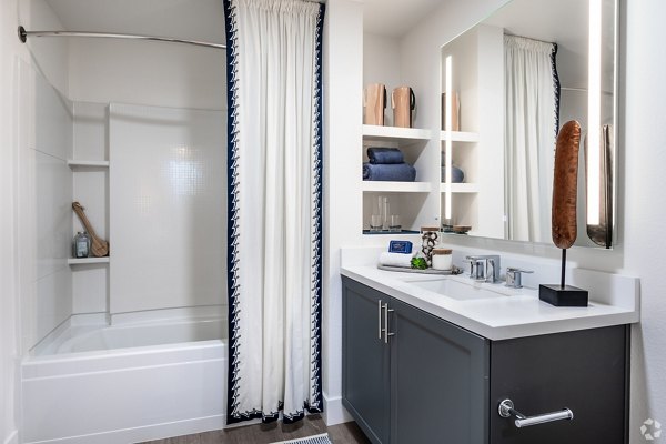 Bathroom with sleek marble countertops and glass shower at Gio Apartments, a luxury residence by Greystar in a modern urban setting
