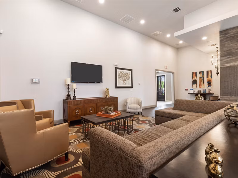 Modern living room and dining area with stylish beige armchairs and a glass coffee table