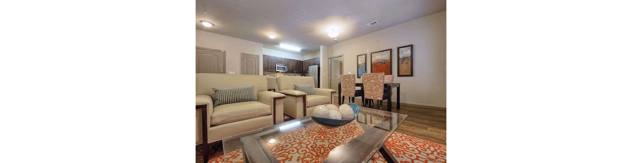 Modern living room and dining area with stylish beige armchairs and a glass coffee table