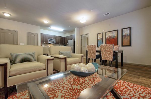 Modern living room and dining area with stylish beige armchairs and a glass coffee table