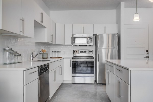 Modern kitchen featuring stainless steel appliances and granite countertops at Brixton Apartments