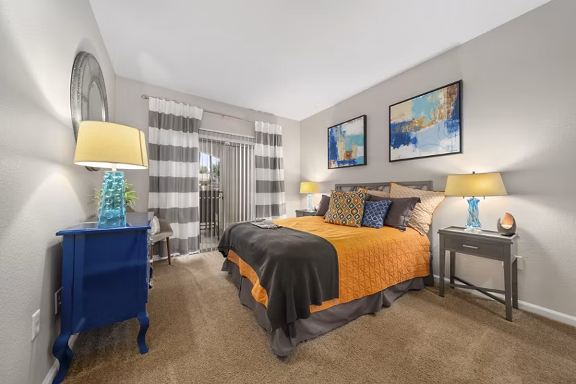 Cozy bedroom with modern decor at Artessa Apartments, featuring large windows and stylish furnishings in a luxury setting