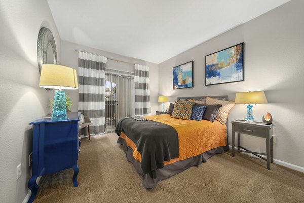 Cozy bedroom with modern decor at Artessa Apartments, featuring large windows and stylish furnishings in a luxury setting