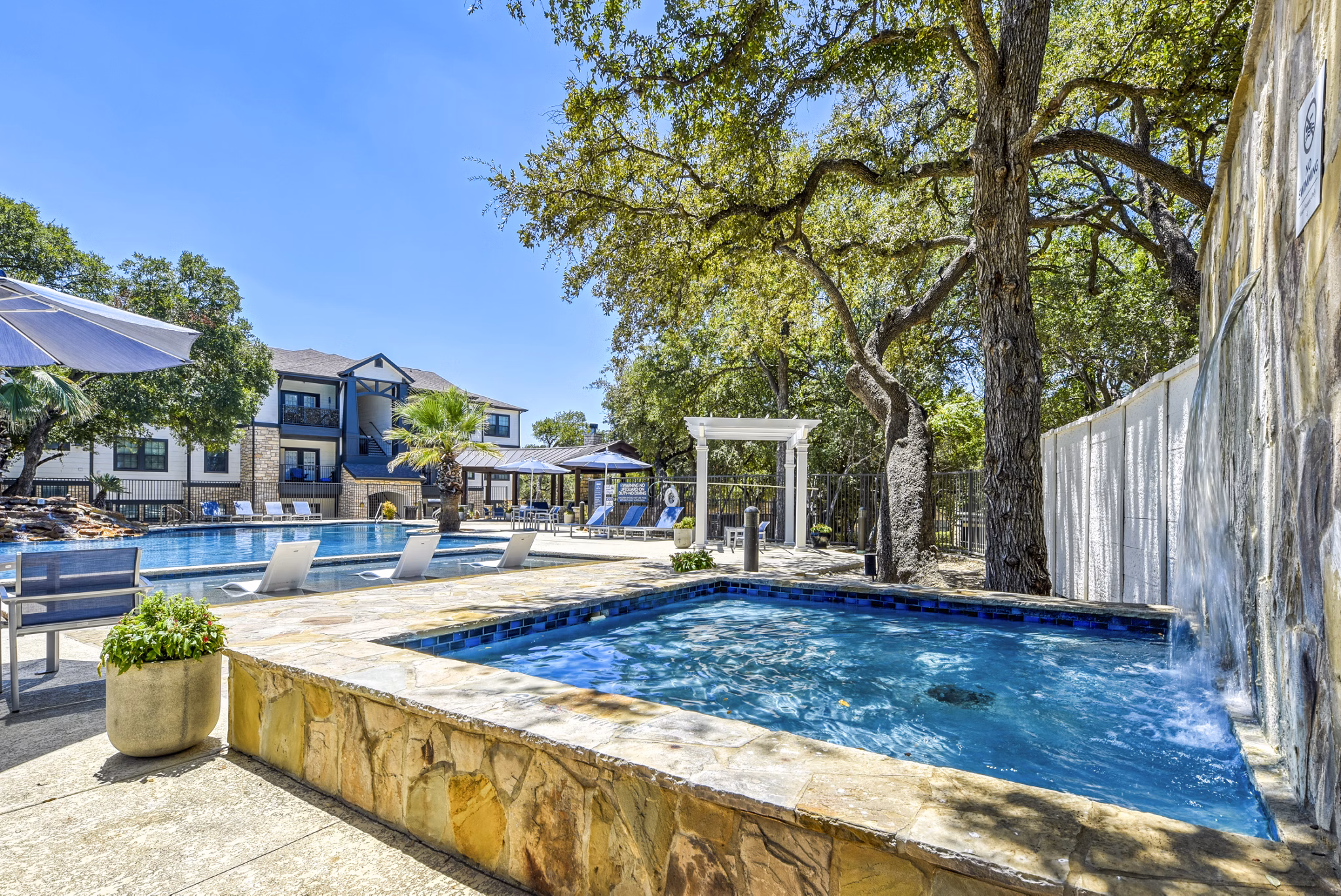 Sunny outdoor pool with loungers and umbrellas at Judson Pointe Apartments, perfect for relaxation and recreation