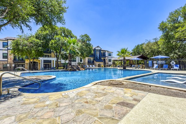 Relaxing poolside oasis at Judson Pointe Apartments with lush landscaping and comfortable loungers, perfect for unwinding on a sunny day