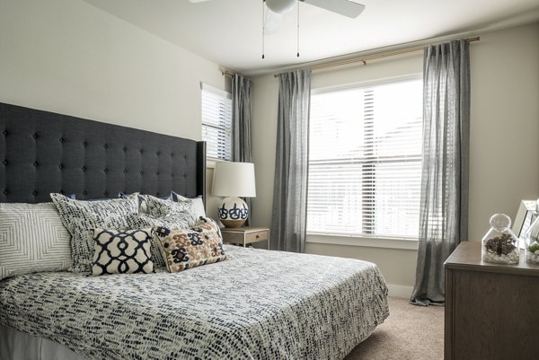 Modern bedroom featuring sleek furniture and large windows in Stella at Riverstone Apartments