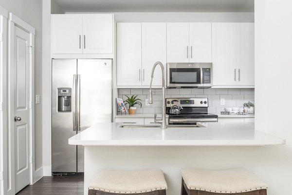Modern kitchen featuring stainless steel appliances and granite countertops in Stella at Riverstone Apartments