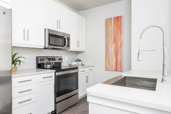 Modern kitchen with stainless steel appliances and marble countertops at Stella at Riverstone Apartments
