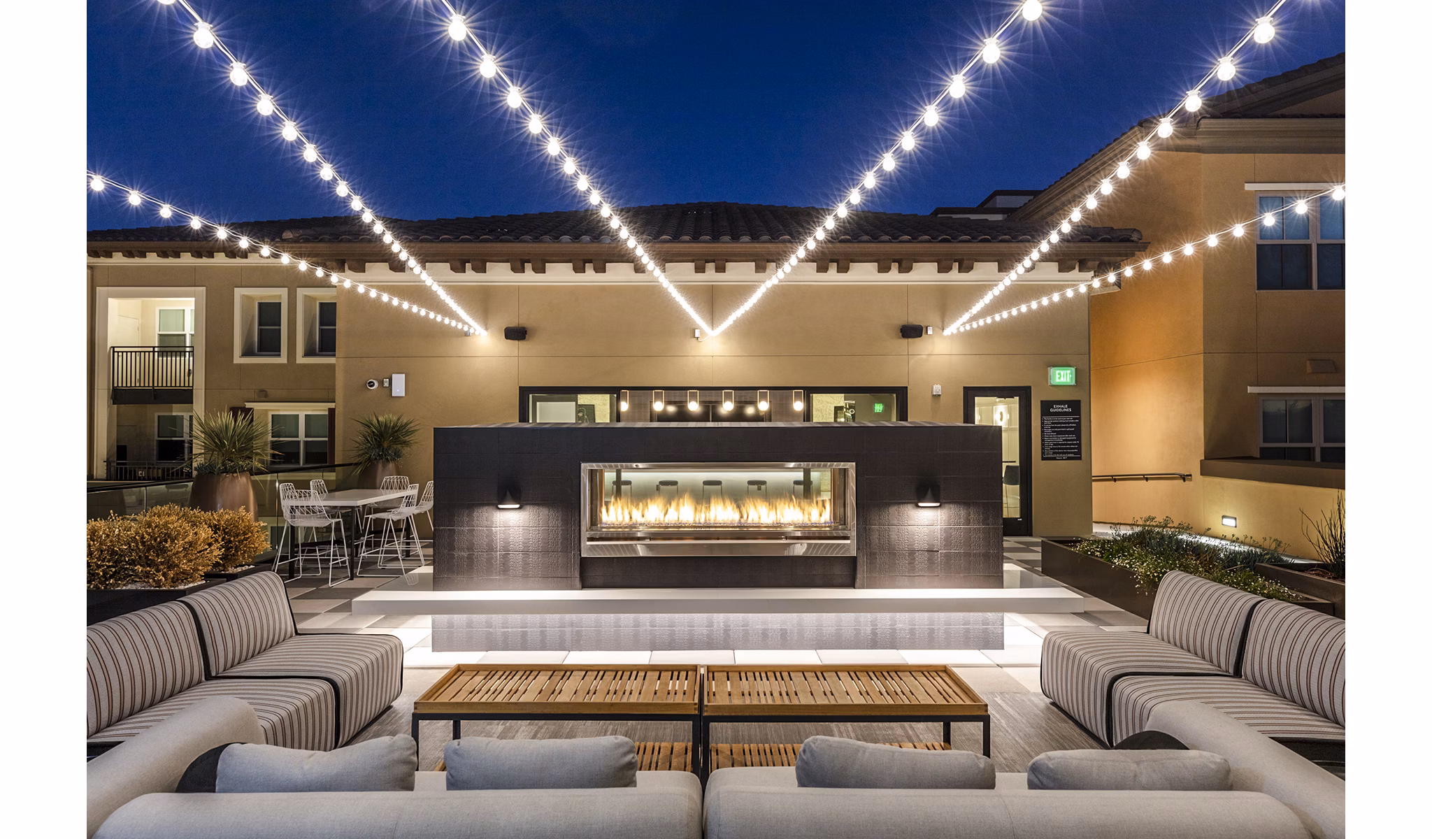Revela Apartments: Cozy patio balcony with a fireplace for outdoor relaxation in Greystar's luxury community