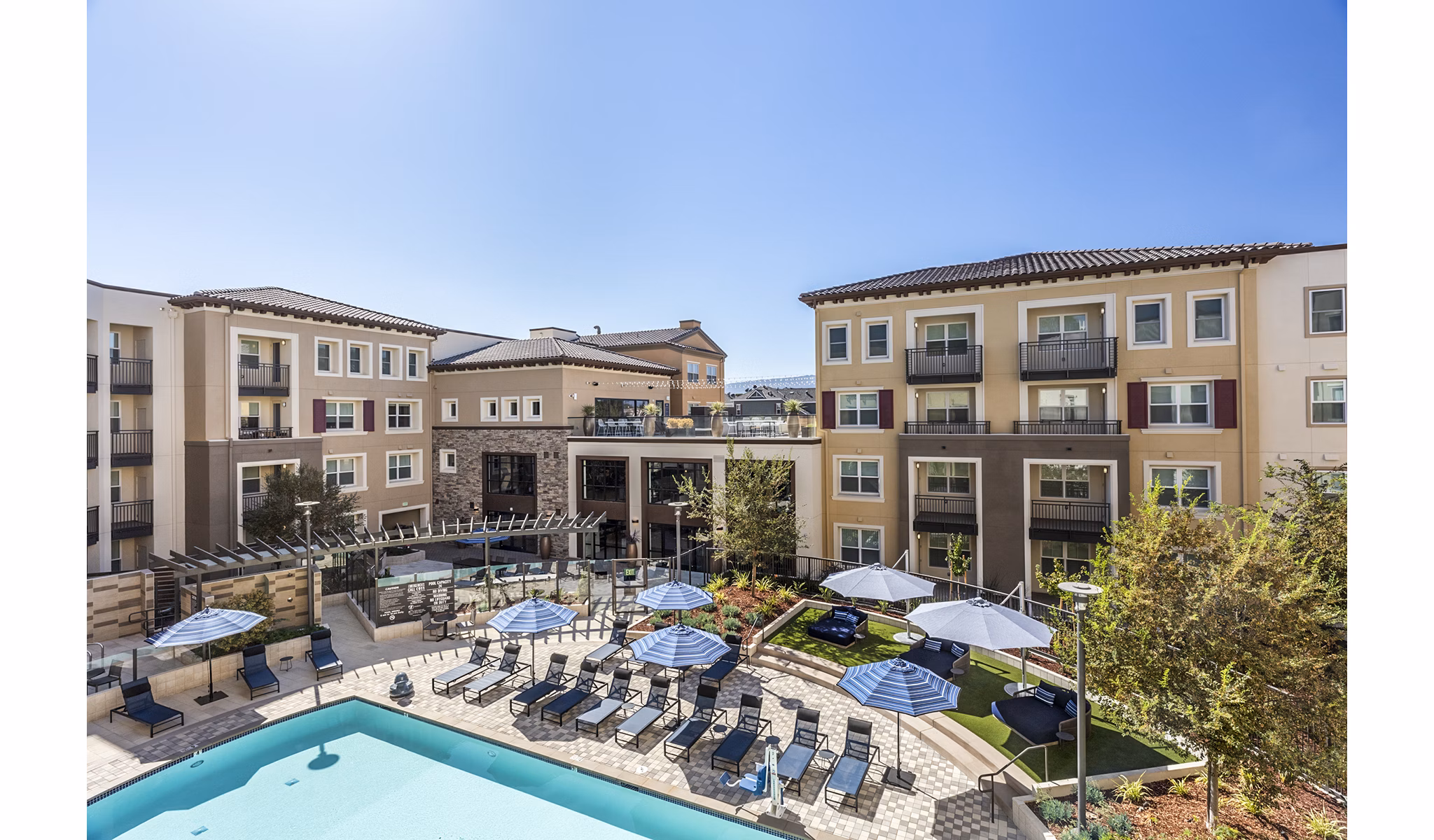 Luxurious outdoor pool area at Revela Apartments with modern seating and lush landscaping, perfect for relaxation and social gatherings