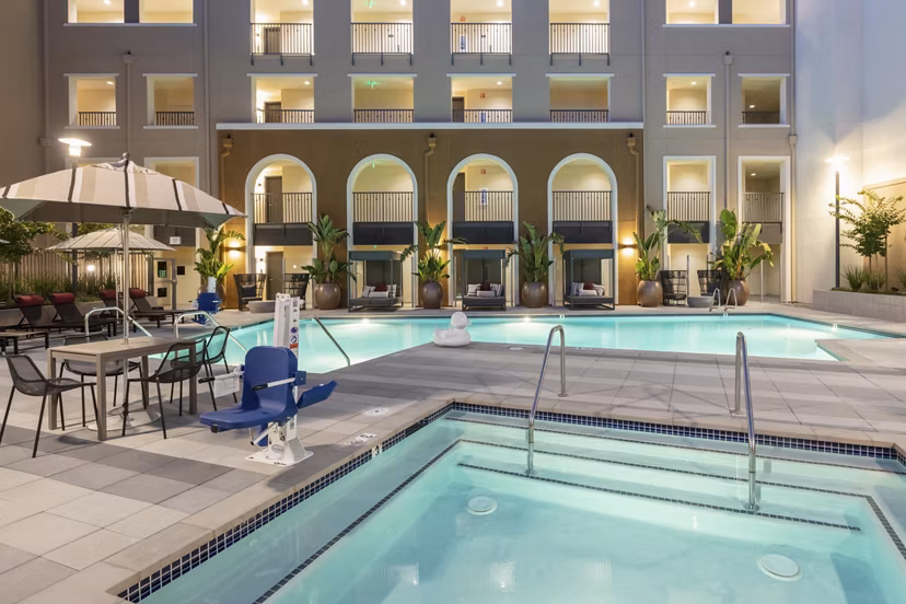 Stunning outdoor pool at Revela Apartments with resort-style seating and lush landscaping
