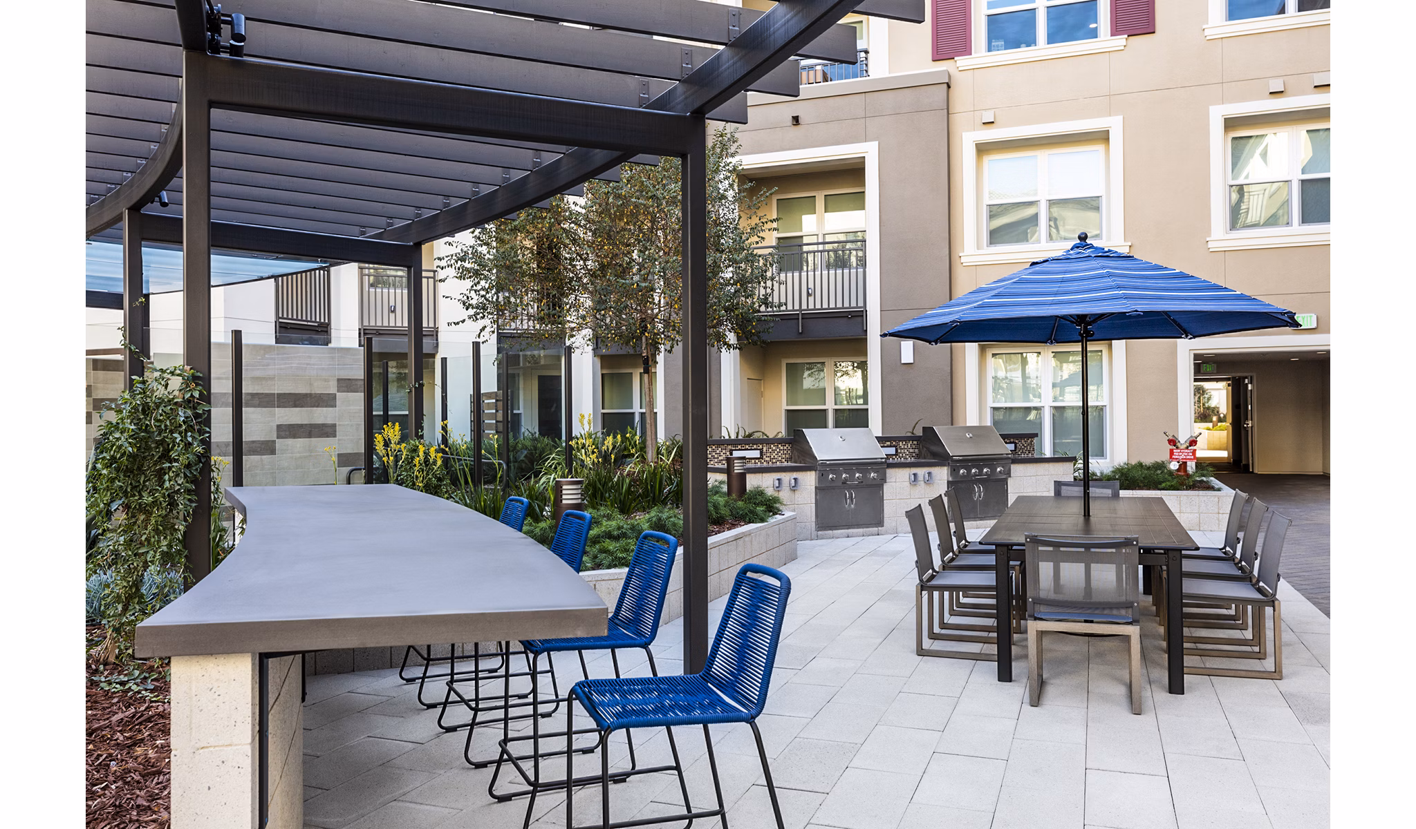 Modern grill area with seating at Revela Apartments, perfect for outdoor gatherings and BBQs in a luxury setting