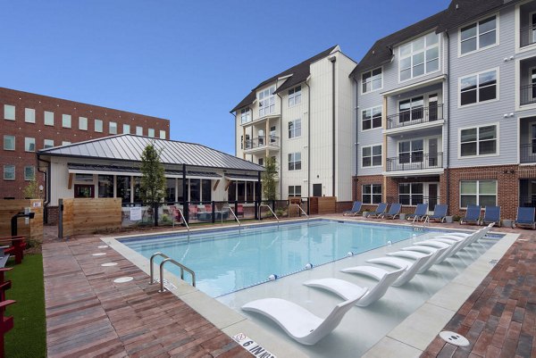 Resort-style pool at Broadstone Junction Apartments with lush surroundings and comfortable loungers