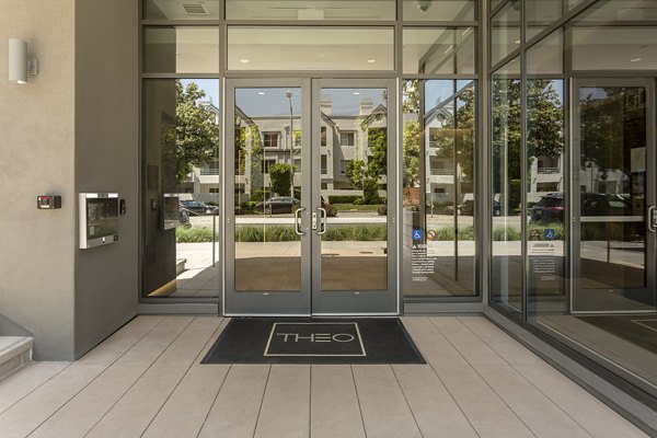 Theo entrance featuring glass doors and welcome mat at luxury apartments