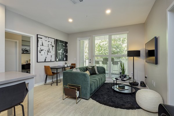 Spacious living room featuring modern decor and large windows at THEO luxury apartments, ideal for comfortable living in urban surroundings