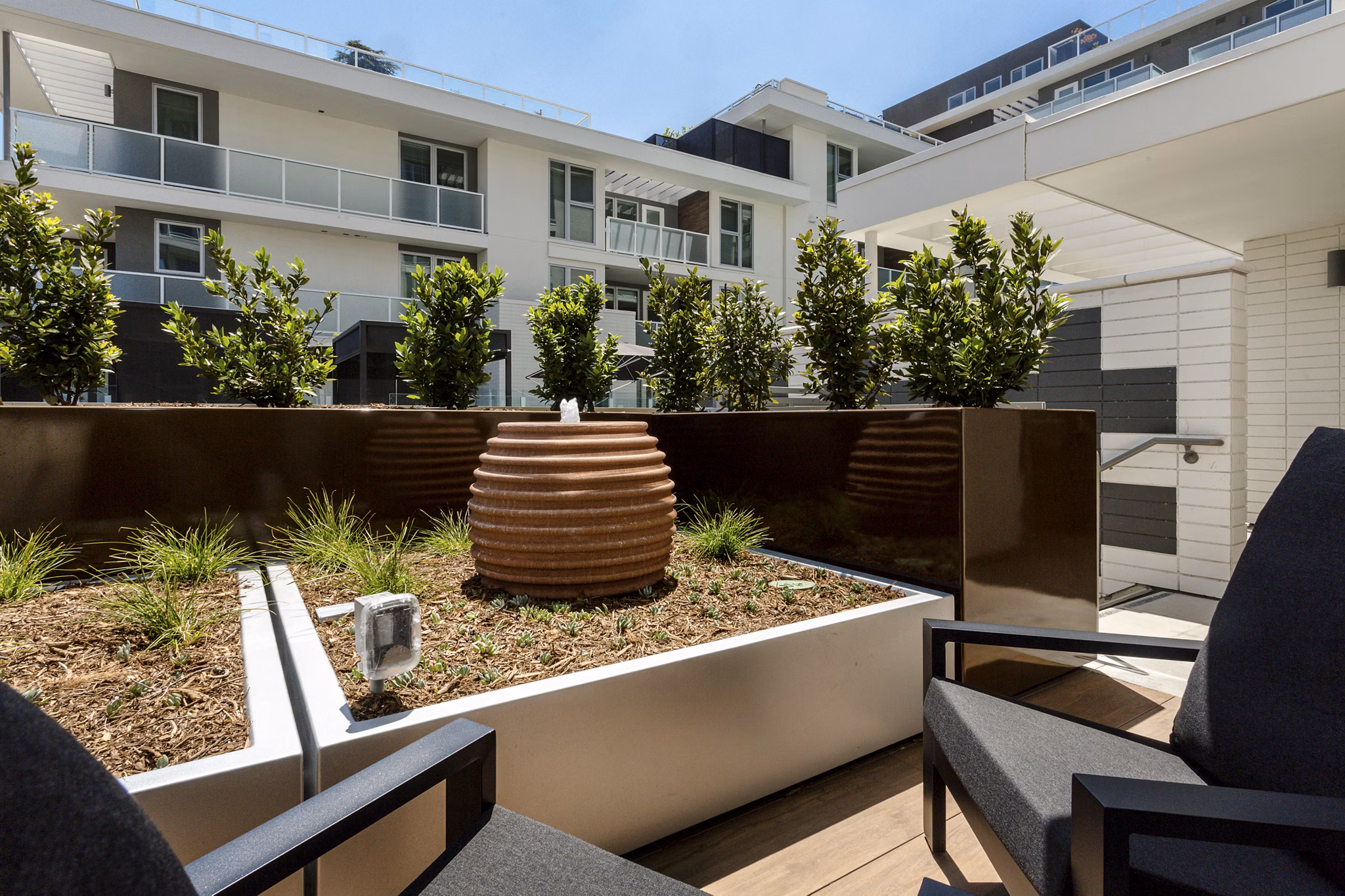THEO: Stylish patio with modern seating and lush greenery in luxury apartments