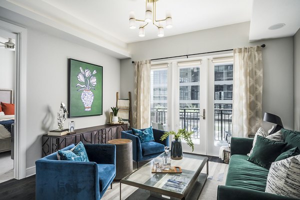 Cozy living room with modern decor and large windows at The Ryan Apartments: luxury Greystar rental in vibrant urban setting