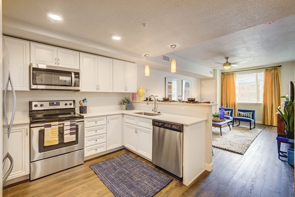 Modern kitchen with stainless steel appliances and quartz countertops at The Zeller Apartments