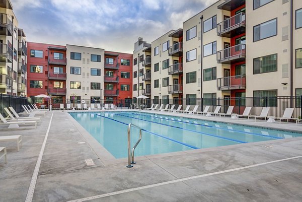Serene outdoor pool at The Zeller Apartments with surrounding lounge chairs, perfect for relaxation and leisure in a luxurious setting