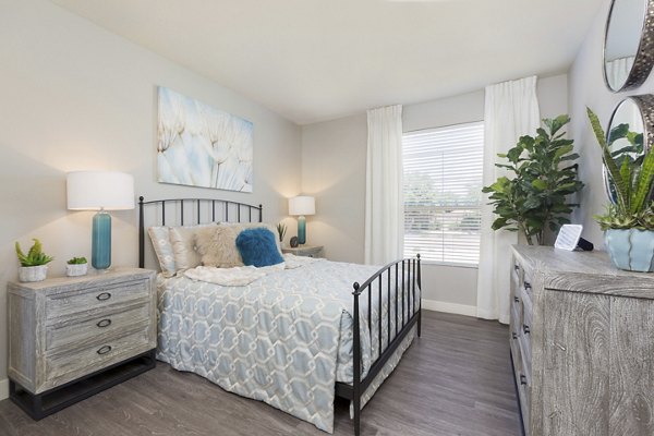 Modern bedroom with sleek furnishings and large windows in ORA Apartments