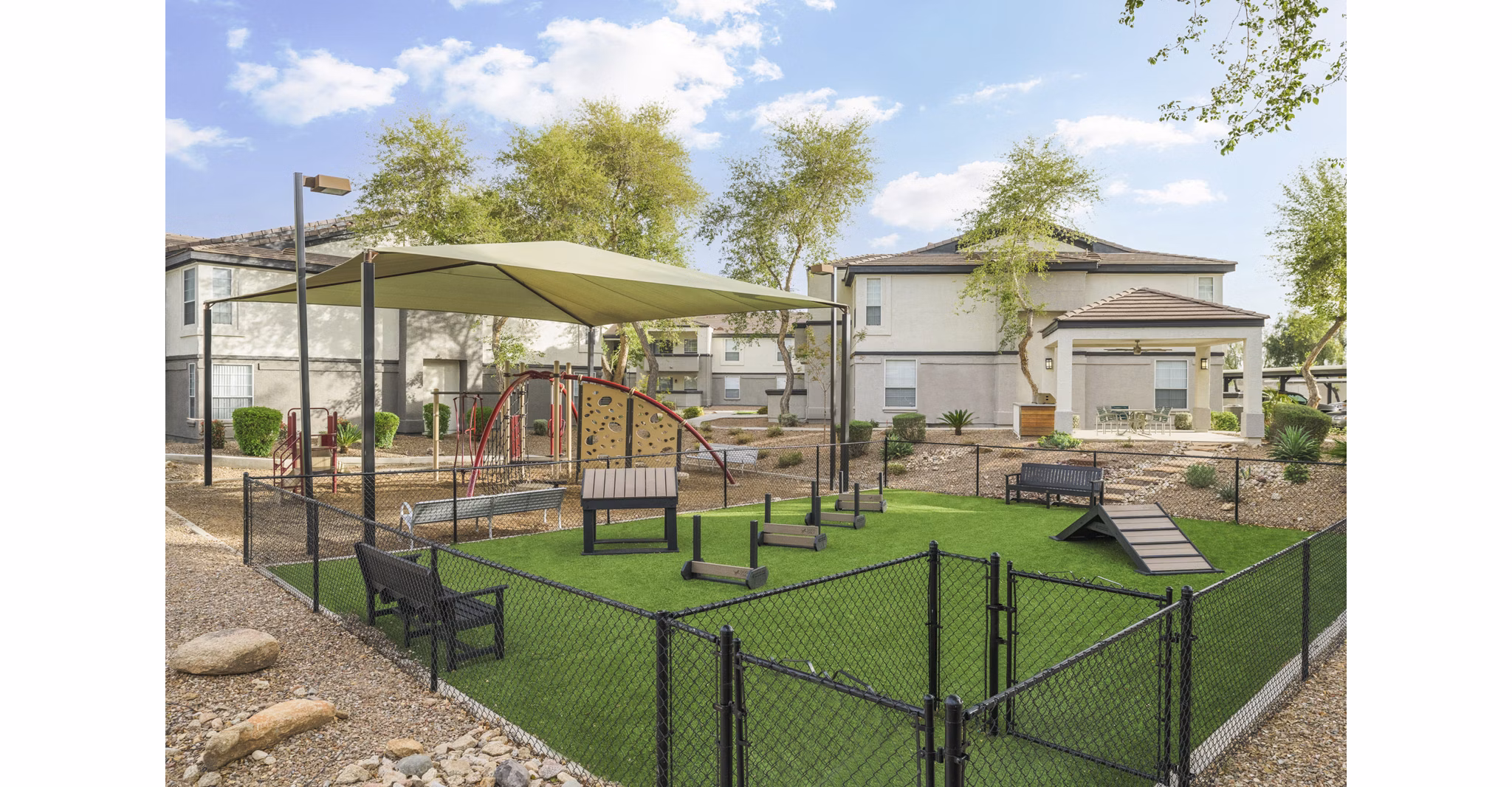 Dog-friendly park at ORA Apartments featuring agility equipment and green space for luxury pet amenities