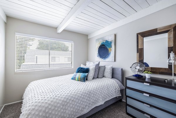 Bedroom featuring modern decor and large windows at Lexington Townhomes Apartments