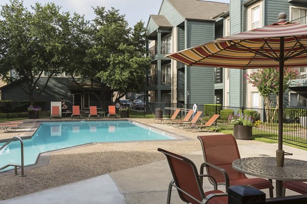 Serene outdoor pool at Scotland Yard Apartments with lounge seating and lush landscaping