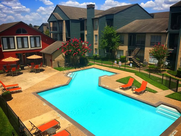 Outdoor heated pool at Scotland Yard Apartments with poolside seating and lush landscaping, offering luxury living in a serene setting
