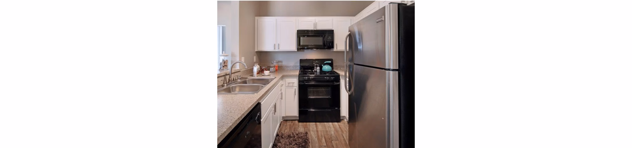Modern kitchen with stainless steel appliances and a marble island in Canyon Crest Apartments