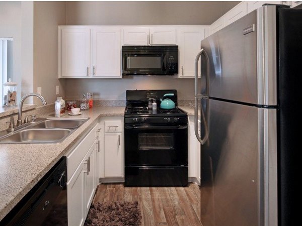 Modern kitchen with stainless steel appliances and a marble island in Canyon Crest Apartments
