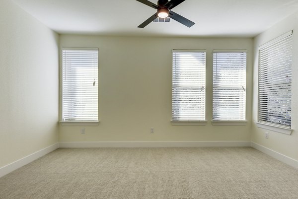Bedroom with stylish decor and large windows at The Tobin Estate Apartments in San Antonio