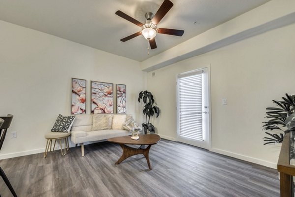 Spacious living room with modern decor at Central Park Commons Apartments, featuring comfortable seating and large windows