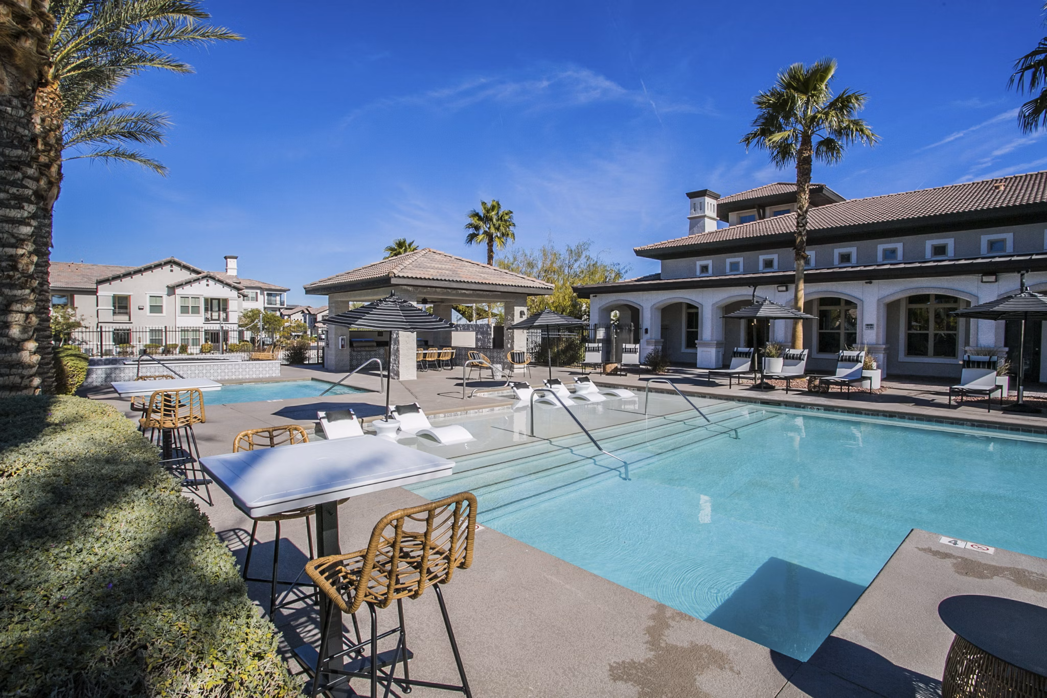 Resort-style pool with lounge areas at Volare Apartments, luxury living in scenic surroundings