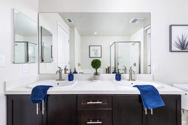 Modern bathroom with stylish fixtures in Portside Ventura Harbor Apartments featuring marble countertops and ample natural light