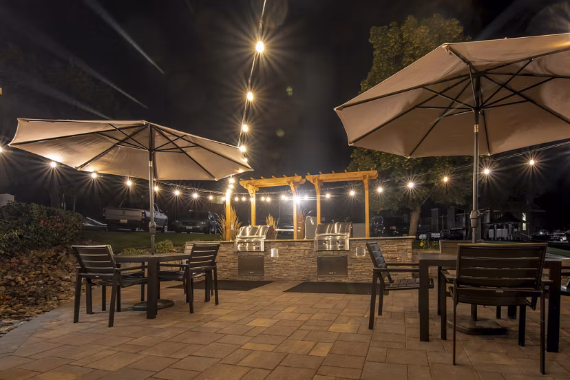 Outdoor grill area at Aspen Ridge Apartments: modern BBQ stations surrounded by lush landscaping for a luxury cooking experience