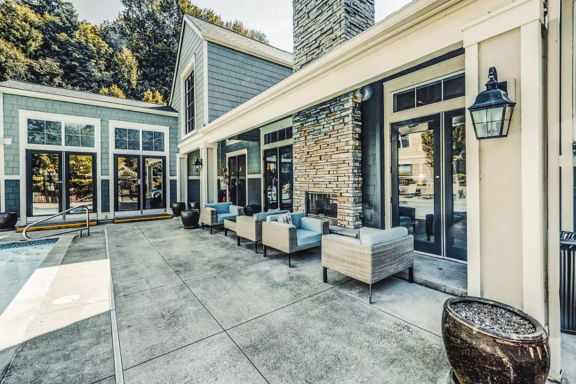 Sunlit pool patio at Bella Vista Apartments with comfortable lounge seating and lush surroundings