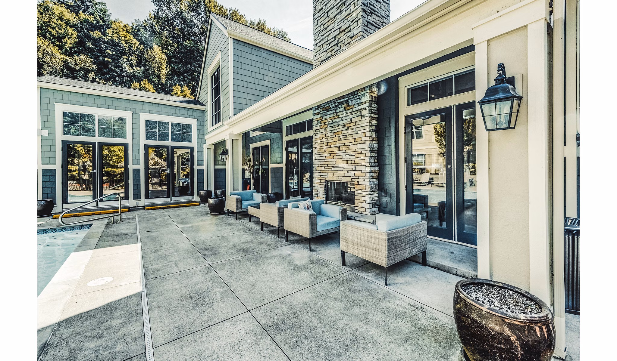 Sunlit pool patio at Bella Vista Apartments with comfortable lounge seating and lush surroundings