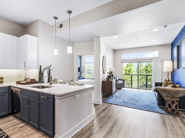 Cozy living room with modern furniture and large windows at Ambrose Apartments, featuring luxury amenities for comfortable living in a Greystar community