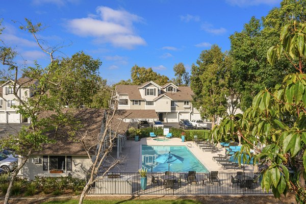 Luxury pool at Flower Fields Apartments with sun loungers and shaded seating areas, perfect for relaxation and enjoyment