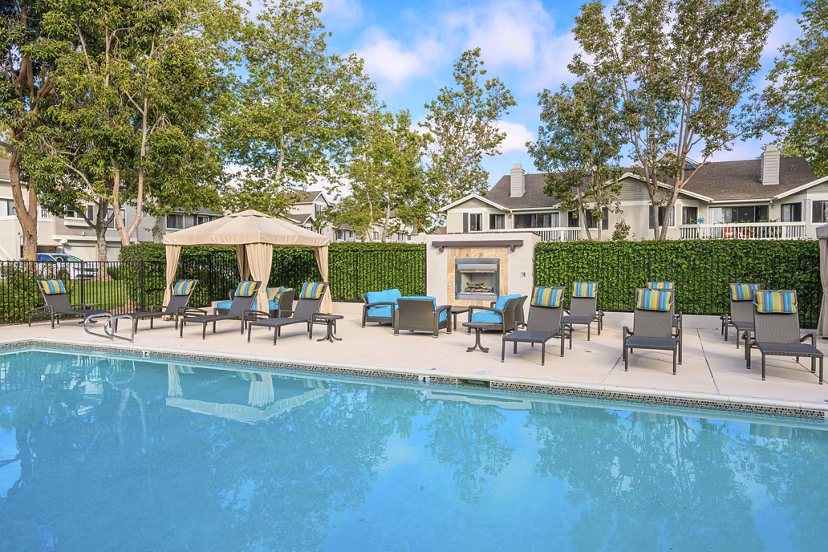 Resort-style pool with palm trees at Flower Fields Apartments, offering luxury living in a serene environment