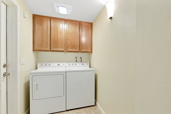 Laundry room with high-efficiency washers and dryers at Montessa At Whitney Ranch Apartments